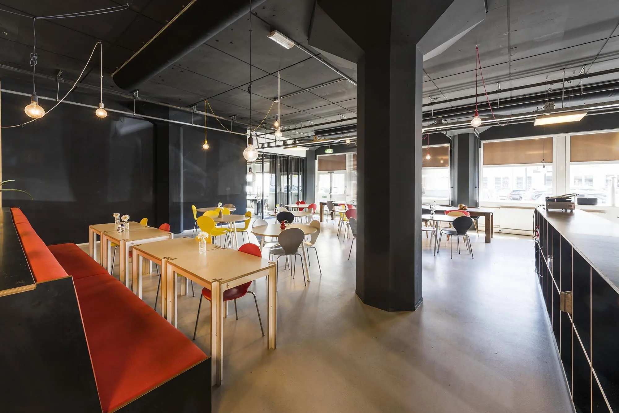 Moderne en kleurrijke kantine met houten tafels en designstoelen aan de Anthony Fokkerweg.